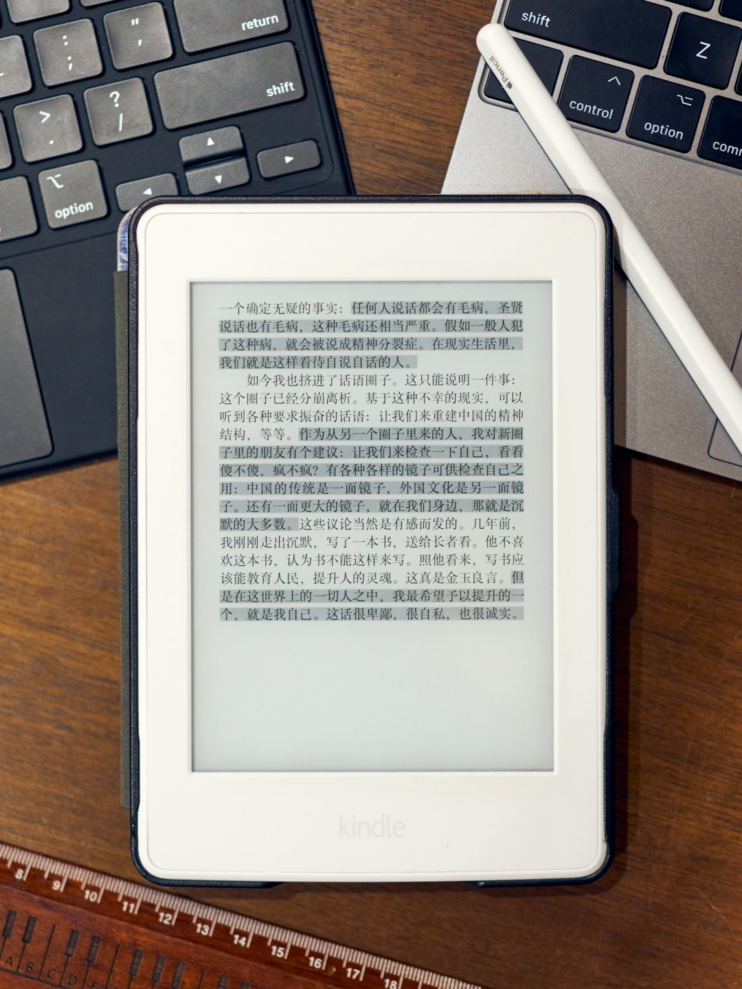 Czytnik e-booków z chińskim tekstem na drewnianym biurku obok laptopa.